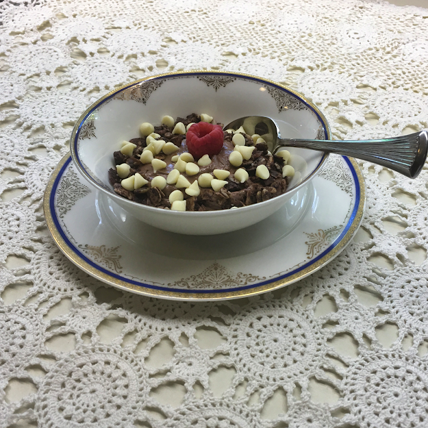 Keto chocolate yogurt pudding with sugar-free crunchy granola and white chocolate chips makes a decadent, sweet, and nutritious low carb breakfast, lunch, or dessert! image - bowl of prepared keto chocolate yogurt pudding topped with sugar free granola and white chocolate chips