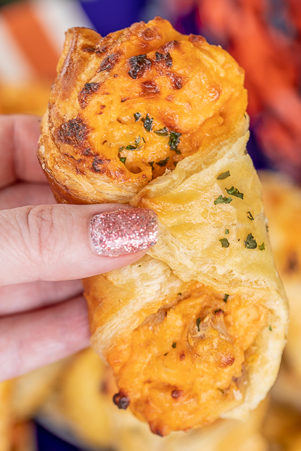 Sriracha Chicken Pastry Puffs - only 5 ingredients! Great recipe for a quick lunch, dinner or party. Chicken, cream cheese, parmesan cheese, and sriracha hot sauce baked in puff pastry. SO good! Can make ahead and freeze for later. We love to serve these with Ranch dressing for dipping. YUM! #chicken #sriracha #partyfood #appetizer #tailgating #gameday holding chicken pastry puff