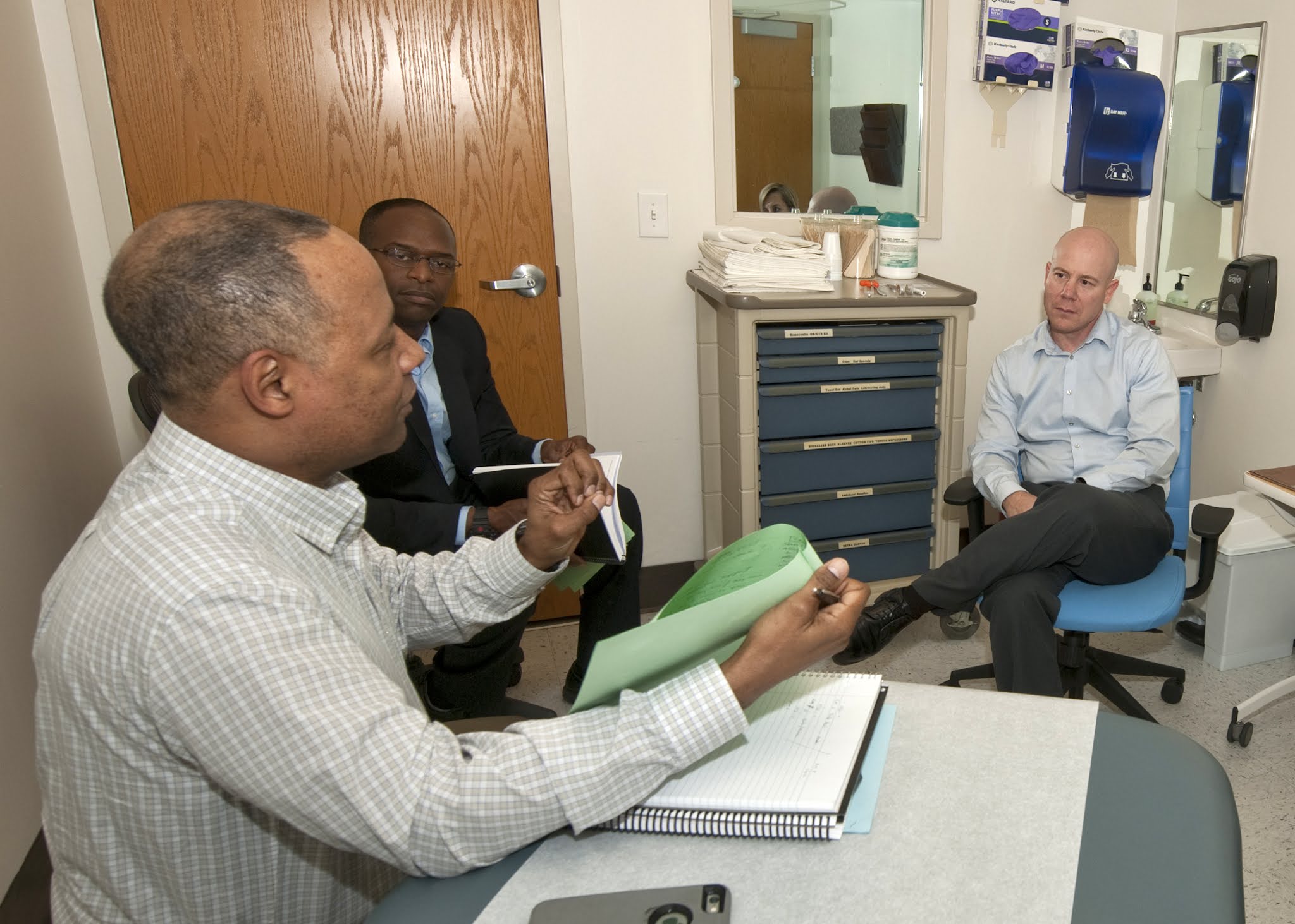 Three men sit in an office and speak with each other about the Chaplains-CARE course.