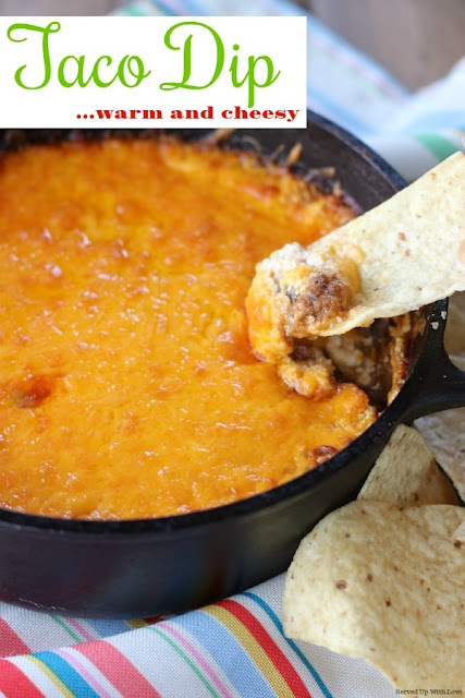 Warm and cheesy taco dip in a cast iron pot with a tortilla chip