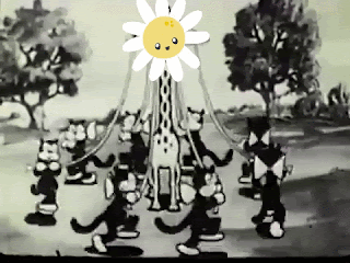Black & white cartoon with some kind of animal creatures dancing around a Maypole-Giraffe with that has a daisy face. The words May Day blink on and off in hot pink letters.