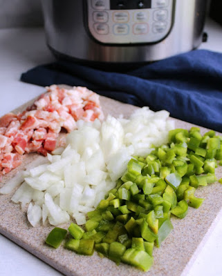 cutting board filled with chopped bacon, onions and green pepper in front of instant pot for maple baked beans