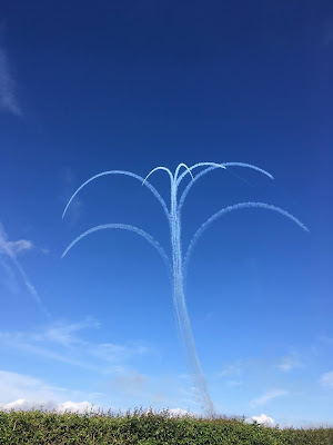 photo of vapour trials from the red arrows display team, against a blue sky 