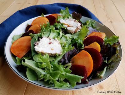 A fun sweet and savory salad with beets, persimmons, goat cheese and pecans lightly dressed in a homemade salad dressing. It is a perfect starter or a great lunch. small bowl of salad ready to eat