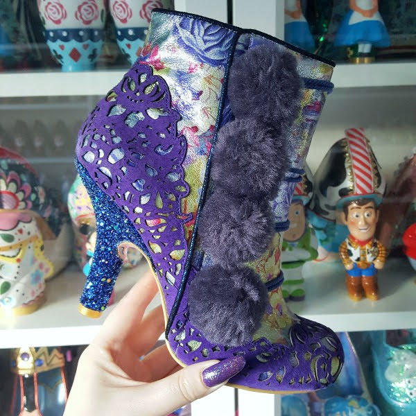 Irregular Choice Slummber Party ankle boot held in hand in front of shoe shelves