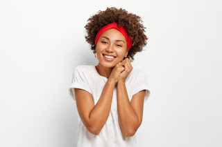 Attractive young woman with afro hairstyle, keeps hands pressed together, wears red headband, casual clothes