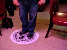 stand on the sticker designating the geographic center of North America at Hanson's Bar in Robinson, North Dakota