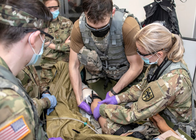 A group of uniformed people practicing administering aid.