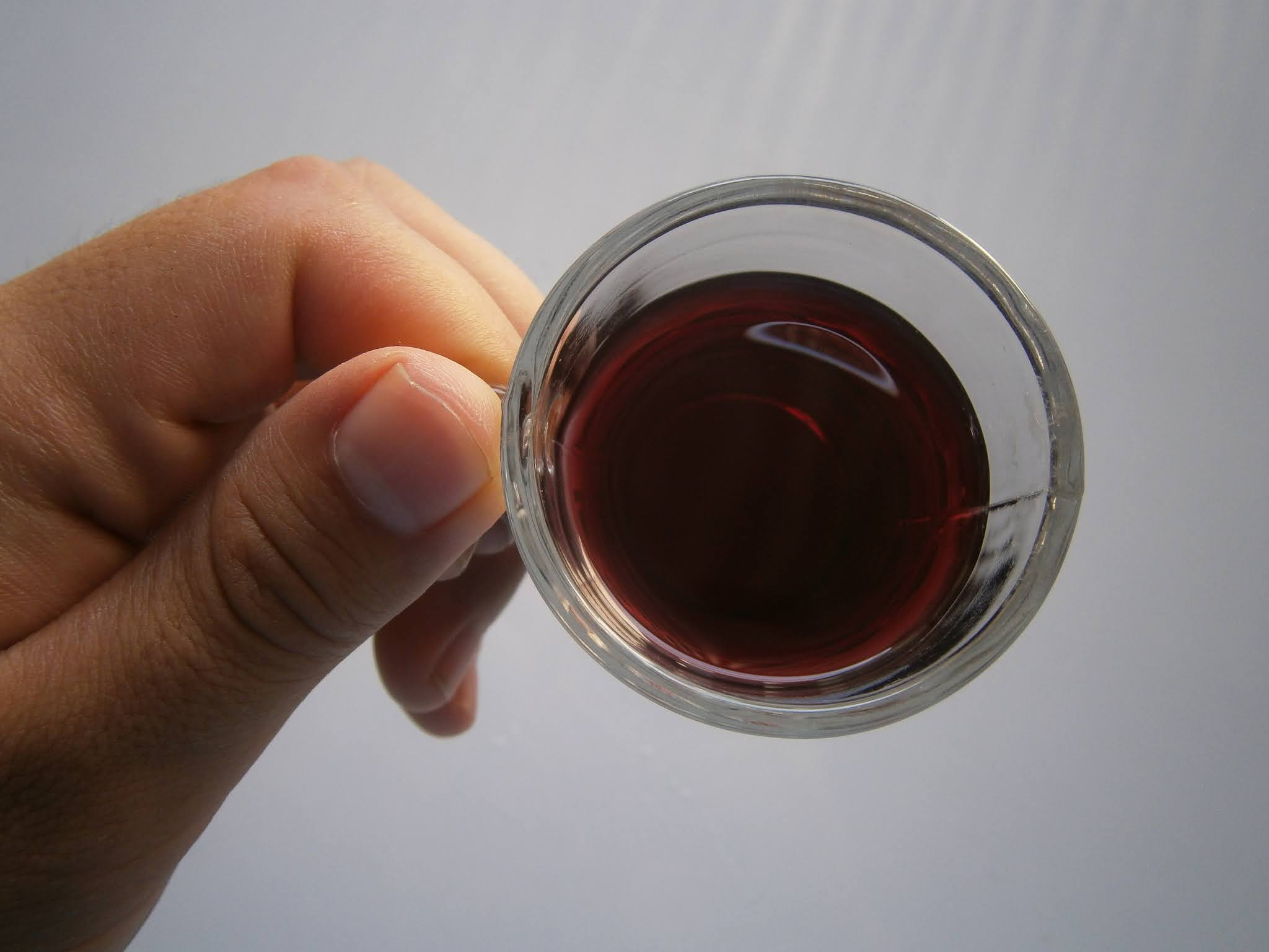 fotografía de Vaso de vino pequeño sostenido sobre una mano de una persona joven