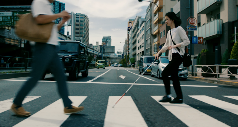 Persona che attraversa la strada con un bastone per ciechi.