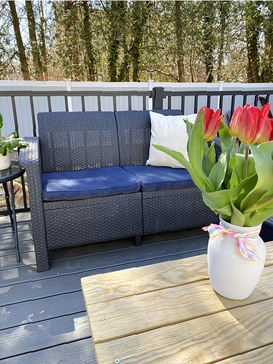 outdoor love seat with painted blue cushions and vase of tulips