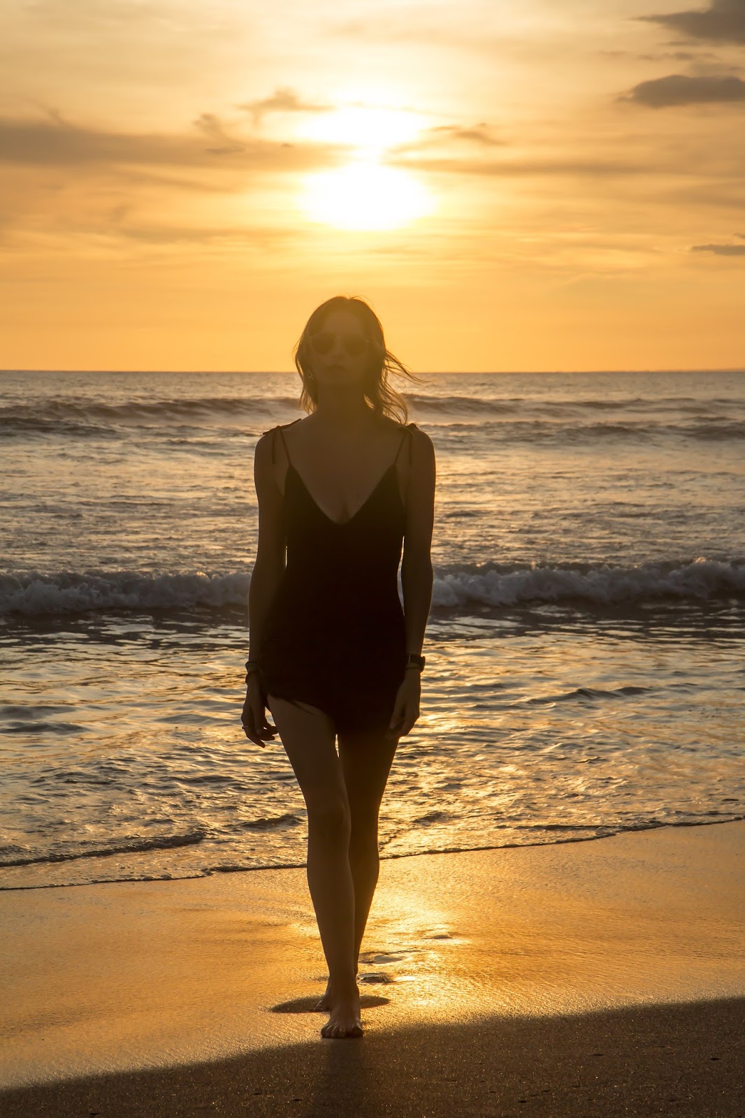 Fashion and Travel blogger, Alison Hutchinson, wearing a one-piece swimsuit at sunset