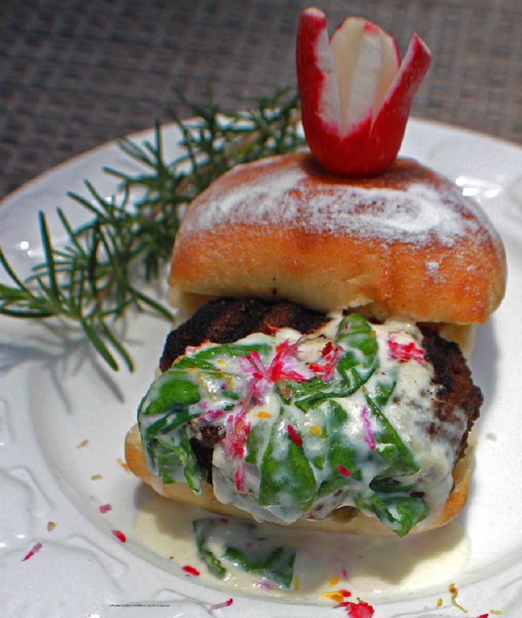 This is a grilled hamburger with a parmesan cheese smoked flavor burger with a creamy spinach sauce with a hint of lemon and grated radish that gives this a peppery taste with a sprig of fresh rosemary and whole radish on top on a ciabotta roll.