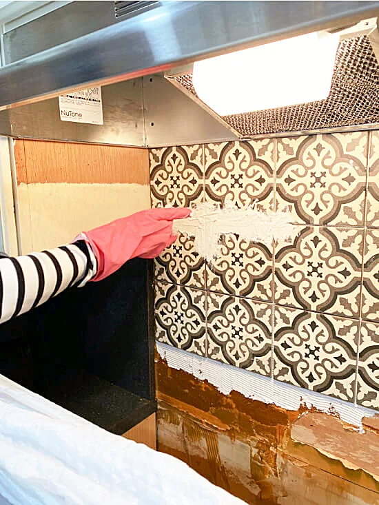 grouting the tiles on the backsplash with gloves