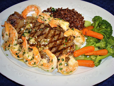PORTIONS: 2 INGREDIENTS 2 thick steaks 1 lb. large Ecuadorian shrimps. Shell removed and deveined 1 tbsp. olive oil 2 tbsp. butter 1 tbsp. minced garlic. 1 tbsp. chopped parsley. Salt and pepper to your own taste. INSTRUCTIONS Leave the steaks at room temperature for 1 hour before cooking. Heat up the grill or top stove griddle and clean it with a bit of oil or the steak`s fat. Dry the steaks with paper towel. If the steaks have blood they will not roast well. Mark and cook steaks the way you like it. Season it with salt while you turn the steaks. In the meantime, heat up a frying pan with the olive oil and lightly cook the garlic until just start to brown. Add the butter, shrimps, salt, pepper and parsley. Cook shrimps until its color is pink. Overcooked shrimps are rubbery. Serve the shrimps with the steaks and pour some of the sauce on the shrimps and over the steaks. Serve with red Jazmin rice, broccoli and baby carrots.
