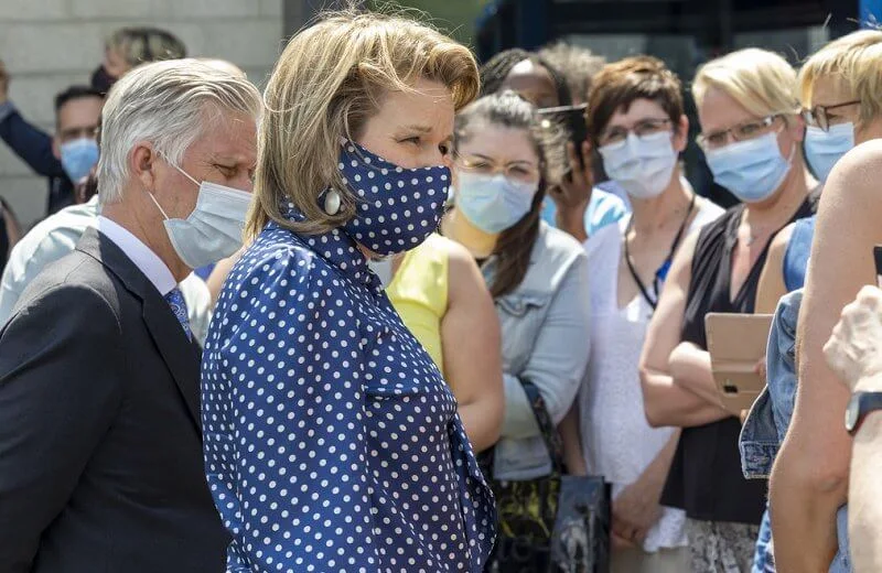 Queen Mathilde wore a navy polka-dot print tie neck blouse from Natan, and polka dot mask, white trousers
