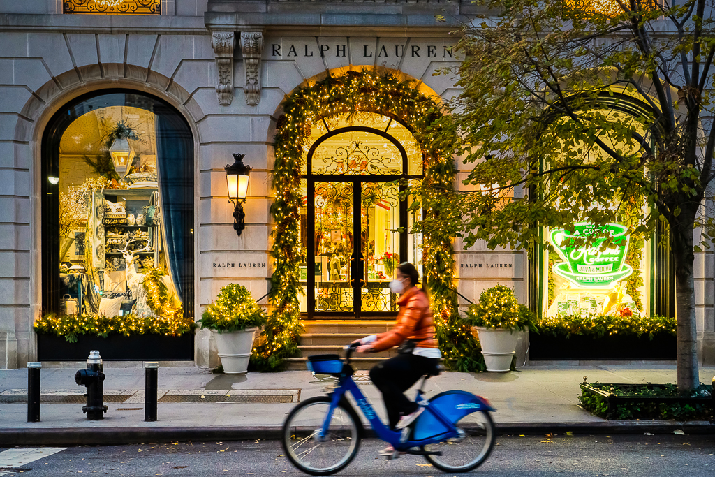 Christmas In New York - Light Happens - Daniel South Photography a photo of a lady riding a bicycle past christmas decorations in new york city