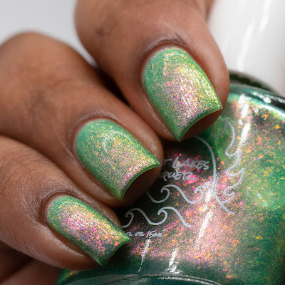 green nail polish with pink to green shifting flakes and shifting shimmer on dark skin