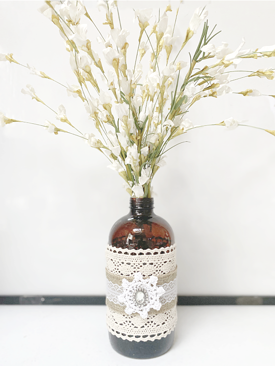 Amber bottle with lace filled with flowers