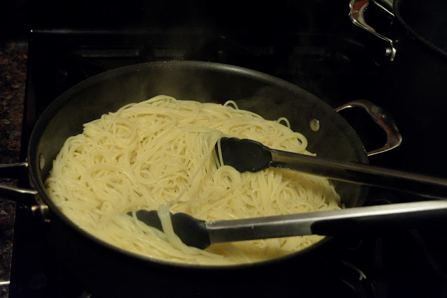 The al dente spaghetti being added to the skillet with the garlic.  
