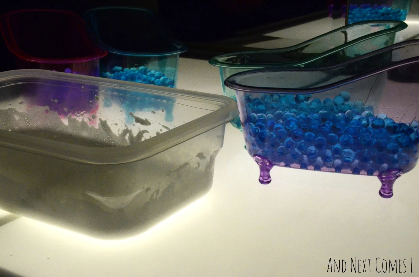 Soap foam, bathtub containers, and water beads on the light table from And Next Comes L