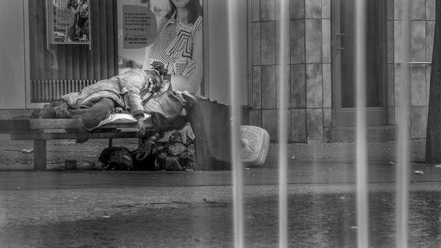 Un mendigo durmiendo en las calles lluviosas de una gran ciudad.
