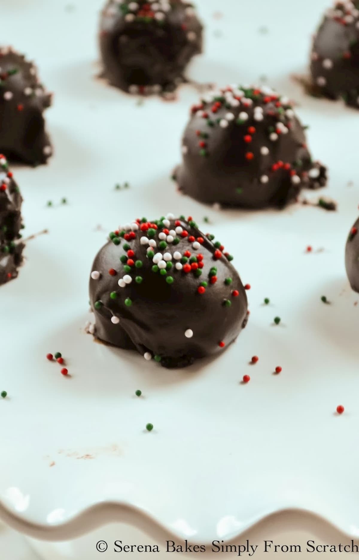 Mint Oreo Cookie Balls with Christmas Sprinkles on a white tray.