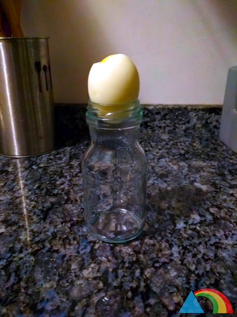 Huevo duro sobre la boca de una botella de cristal