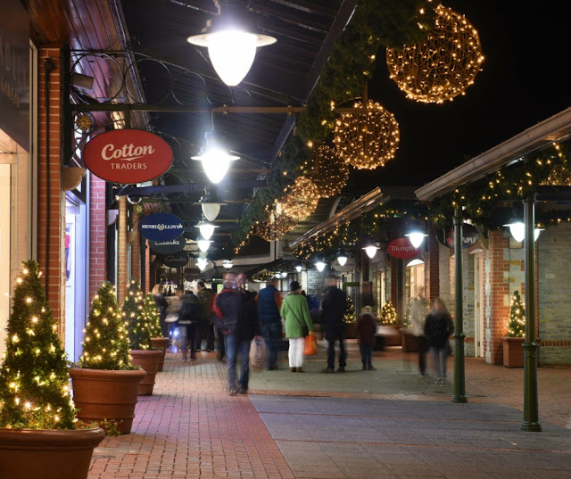 high street shops decorated with christmas decorations, lit up in the dark