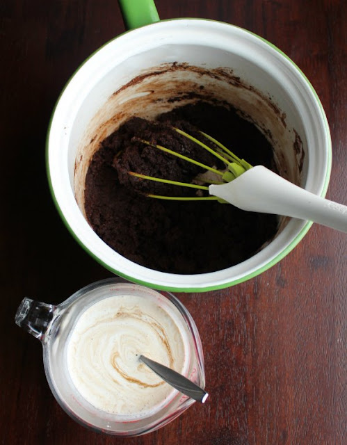 This glossy fudgy chocolate frosting is the perfect wrapper for a cake. It spreads so smoothly and it packs a big flavor punch. You are going to love this vintage recipe for deliciously shiny fudge frosting! butter and cocoa mixture in saucepan and measuring cup with cream and sour cream mix