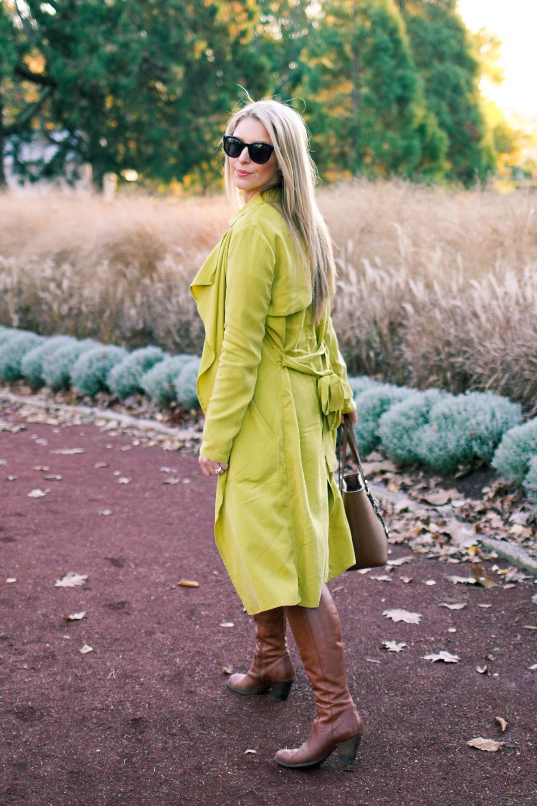 The Goldfields Girl styling maternity fashion. She wears black maternity dress, green jacket, statement gold necklace, brown boots and Michael Kors bag.