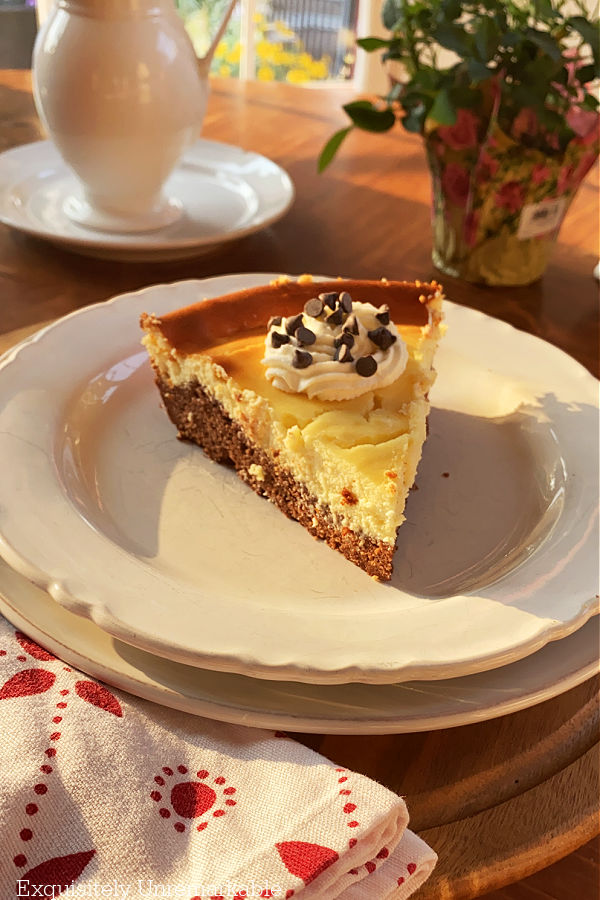 Cheesecake With Brownie Bottom Crust on table with whipped cream and chocolate chips
