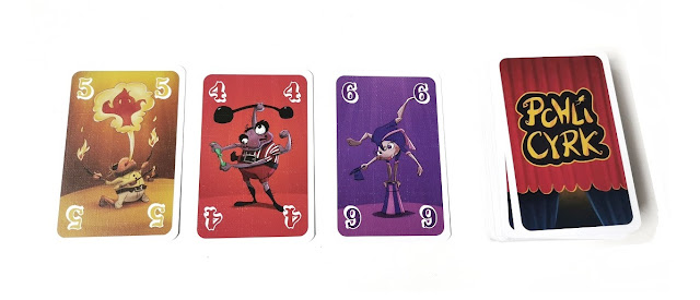Pchli Cyrk gra na imprezę, na zdjęciu stos kart dobierania oraz trzy odkryte już karty w różnych kolorach