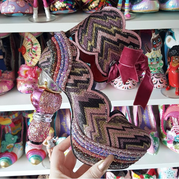 Irregular Choice Wish Magic shoe in hand with shoe shelves in background