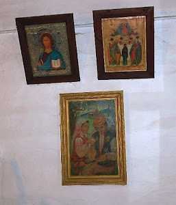Obrazy i fotografie wiszące na ścianach izby.