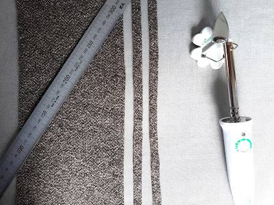 Small rectangular lengths of fabric laid out on an ironing board with a steel ruler and a mini quilting iron.