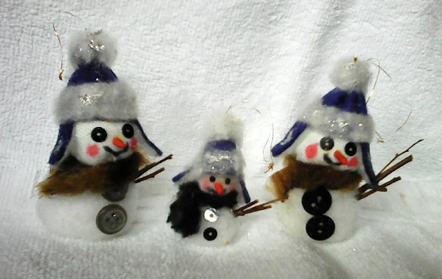 trei oameni de zapada din pompon in decor de iarna