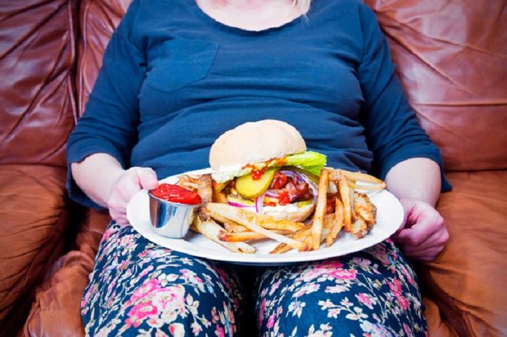 Overweight woman with a large unhealthy meal