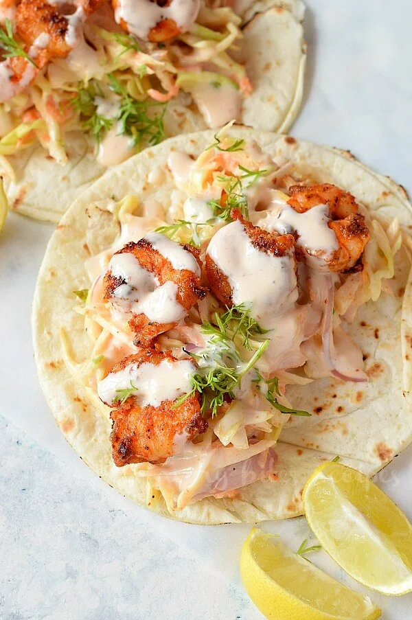 white background with spicy sriracha shrimp tacos with cilantro lime slaw