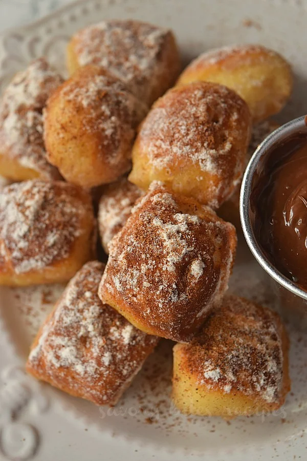 close up of baked cinnamon sugar pretzel bites served ona white plate along with chocolate dip