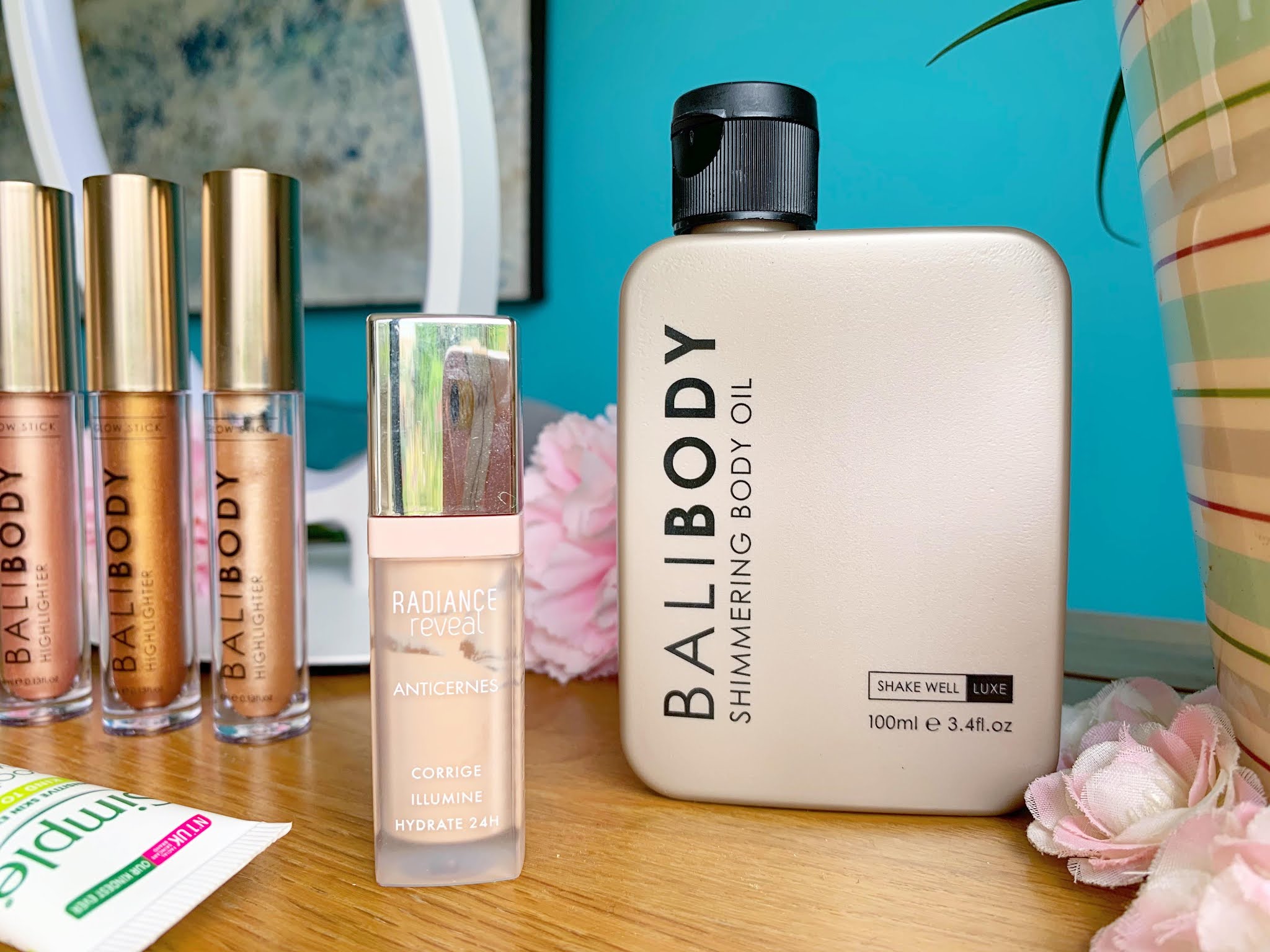 Bali Body Shimmering Body Oil and Bourjois Radiance Concealer Bali Body Shimmering Body Oil and Bourjois Radiance Concealer on a side table with a blue background