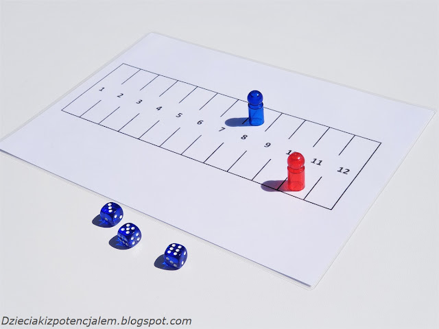 zdjęcie przedstawia planszę do gry marinetti, na niej dwa pionki, czerwony na polu 11 a niebieski wraca już na start i jest na polu 8, na pierwszym planie leżą kostki