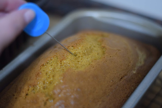 A cake pin being poked into the pumpkin bread. 