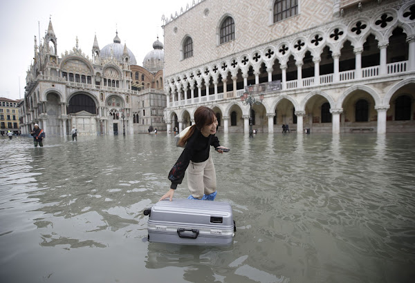 A tourist pushes her floating luggage in the flooded Piazza San Marco