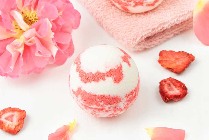 How to make a strawberry milkshake bath bomb without cornstarch. These cute and unique bath bombs would make a great gift. These natural bath bombs are fizzy and moisturizing. This DIY easy recipes uses essential oils for natural scents.  Home made pretty and cool bath bombs.  If you need ideas for summer bath bombs, try this recipe.  #bathbomb #diy #strawberry