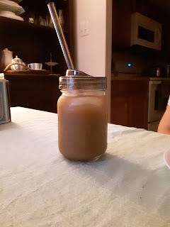 iced coffee in a glass jar with a reusable plastic lid and spoon