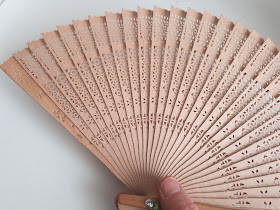 Hand holding a wooden fan.