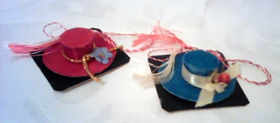 doua martisoare palarie: una rosie, una albastra, carton invelit in material textil