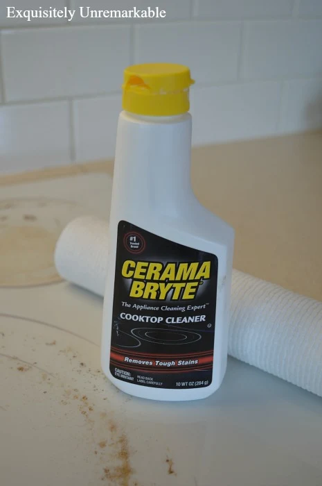 Cerama Bryte Cleaner Bottle on a dirty white stove next to paper towels