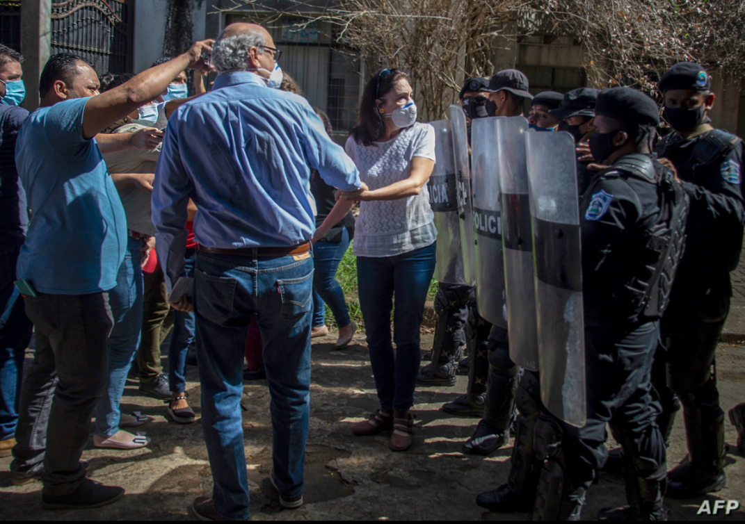 El periodista nicaragüense Carlos Fernando Chamorro, director de los medios de comunicación Confidencial y Esta Semana, es empujado por la policía antidisturbios frente a las oficinas de El Confidencial en Managua el 14 de diciembre de 2020 / AFP